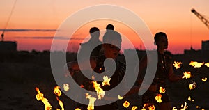 Fire dancers against sunset. A young woman poses with her fire hoop against the sunset during her dance performance.