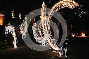 Fire dancers swing, spinning fire and man juggling with bright s
