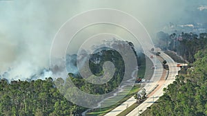 Fire department firetrucks extinguishing wildfire burning severely in Florida jungle woods. Emergency service vehicles