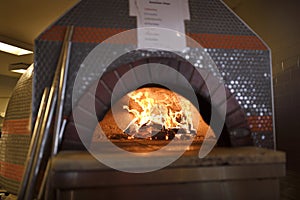 Fire in dome ceramic wood burning pizza oven at Amsterdam Brewhouse Toronto