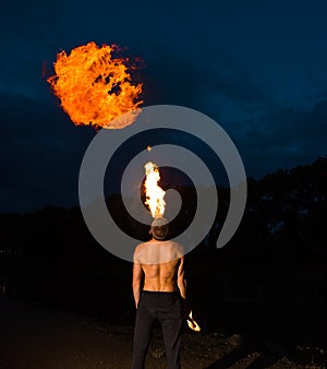 Fire-eater blowing a large flame from his mouth