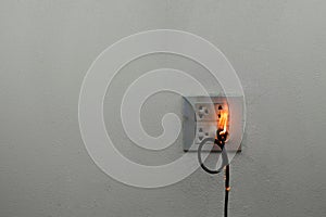 On fire electric wire plug in the receptacle at wall partition