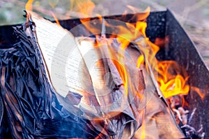 Fire engulfs the pages of an open book. Burning a book photo
