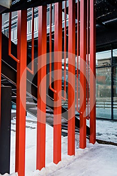 Fire escape ladder or emergency exit with steel staircase on wall of modern industrial building with red metal