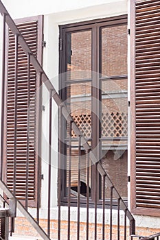 Fire Escape stairs beside window, brick wall in glass reflection. Architecture background