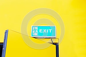 Fire EXIT green emergency exit sign Attached to top of yellow background door office.