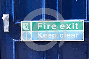 Fire exit keep clear sign on building blue exit door