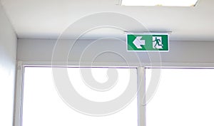 Fire Exit sign on the ceiling entry the fire escape, green safety light symbol isolated in white window. Caution for warning.