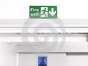 Fire Exit sign on the wall entry the room, green safety symbol icon isolated in the white door. Caution for warning in dangerous.