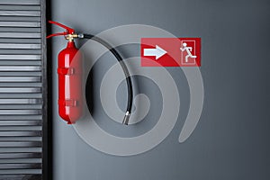 Fire extinguisher and emergency exit sign on wall indoors