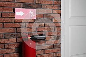 Fire extinguisher and emergency exit sign on wall indoors