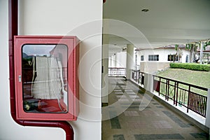 Fire extinguisher and fire hose reel in hotel corridor. Fire hoses rack for use.