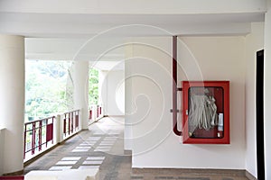 Fire extinguisher and fire hose reel in hotel corridor. Fire hoses rack for use.