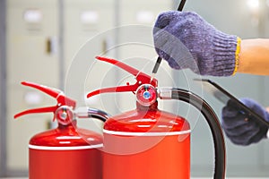 Fire extinguisher has hand engineer inspection checking pressure gauges to prepare fire equipment for protection and prevent in