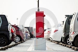 Fire extinguisher and hydrant box at the center of a building\'s parking lot.