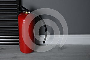 Fire extinguisher near grey wall. Space for text