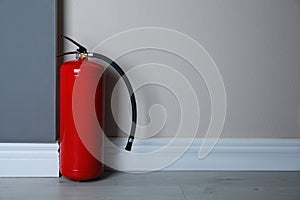 Fire extinguisher near light wall. Space for text