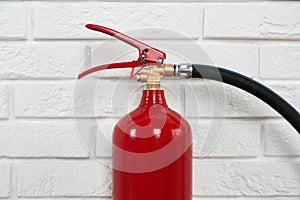 Fire extinguisher near white brick wall