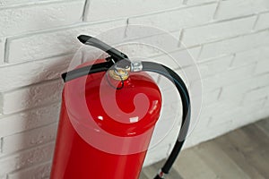 Fire extinguisher near white brick wall, closeup