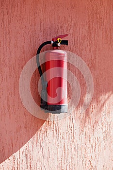 Fire extinguisher on the terracotta exterior wall of the house