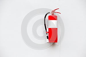 Fire extinguisher on white brick wall background.