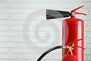 Fire extinguishers against white brick wall. Space for text
