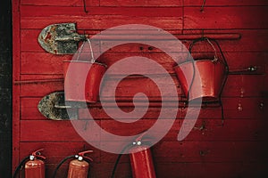 Fire extinguishing tools. Shovels, buckets, fire extinguishers on a red wooden wall