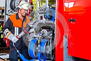 Fire fighter checking hydraulic cutter at fire engine