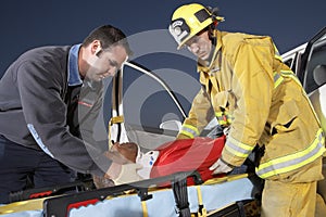 Fire Fighter And Paramedic Assisting Man At Crash Site