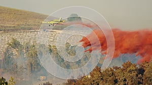 Fire fighter plane drops fire retardant on a forest fire in the hills