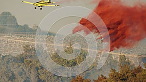 Fire fighter plane drops fire retardant on a forest fire in the hills