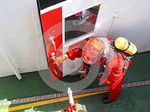 fire fighters is entering an accommodation with fire hose during fire drill on a cargo ship out bulk carrier