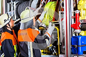 Fire fighters loading hoses into operations vehicle