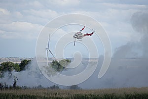 A Fire Fighting Helicopter Amongst The Smoke Of A Wildfire