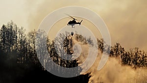 Fire fighting helicopter dropping water on wildfire