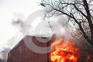 Fire fighting helicopter silhouette with bambi bucket for Ñarrying water to put out a massive building city fire, process of put