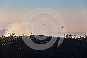 Fire-fighting helicopter with a water bucket fighting a fire on