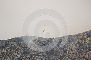 A fire fighting water bomber dropping water on a forest fire on top of the Kozjak mountain in Croatia. Summer wildfires are very