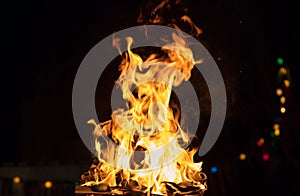 Fire with flames and bokeh lights. Big blaze on black blurred background. Close up view with details, space for text.