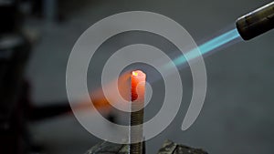 Fire of gas burner heats up red-hot the metal bolt closeup