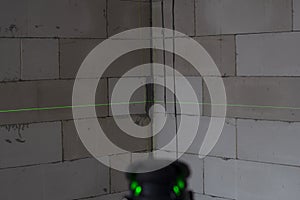 Fire green laser beams on the walls that are being built in construction site with measuring tool to hold the level.