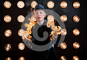 The fire is in his hands. Professional magician showing trick. Light bulbs on background