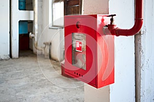 Fire hose in red box. Pipe roll for fire emergency in red metal cabinet on grey whitewashed wall as part of fire