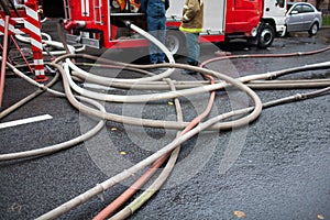 Fire hoses on the background of fire trucks and firefighters at work