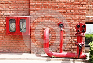 Fire hydrant,hose and pipes inserted on brick wall