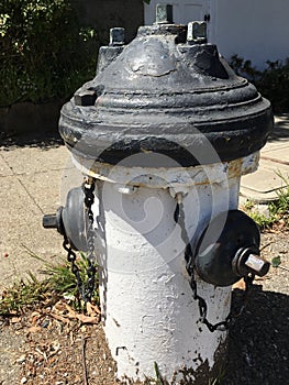 A fire hydrant wearing a black hat and matching black gloves.