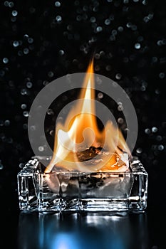 Fire inside square glass ashtray in the dark