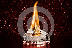 Fire inside square glass ashtray in the dark