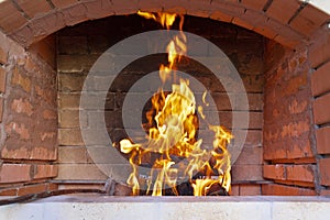 The fire is lit in a summer brick oven for barbecue, grill and other outdoor dishes