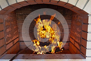 The fire is lit in a summer brick oven for barbecue, grill and other outdoor dishes